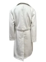 Charity Jones smiling while holding a cup of cocoa, wearing a bright crimson red trench coat with gold-toned button accents.