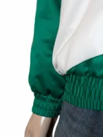 Detailed view of a green and beige satin bomber jacket with a stand-up collar and elastic cuffs.