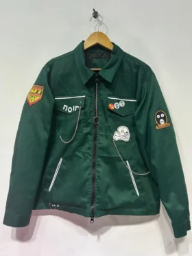 Noel Fielding as Vince Noir wearing a slim-fit, high-shine black PVC biker jacket with an oversized silver zipper.