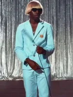 Tyler the Creator in Igor blue suit and blond wig with sunglasses on stage during the IGOR era with silver curtain backdrop