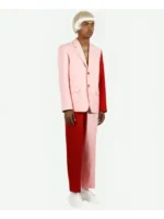 Male model side view wearing Tyler the Creator Igor pink blazer with red trousers and blond wig on white background