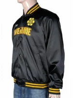 A person wearing a black satin Disney Powerline Tour Bomber Jacket with yellow "POWERLINE" branding on the front and a "Stand Out World Tour '95" graphic on the back.