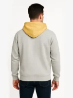 Rear view of a man wearing the heather grey Fear of God Essentials NBA Pacers hoodie, displaying the plain back panel and the contrasting yellow hood.
