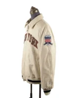 Straight-on front view of a full-zip collared jacket on a mannequin, featuring large arched block lettering across the chest and a striped waistband and cuffs.