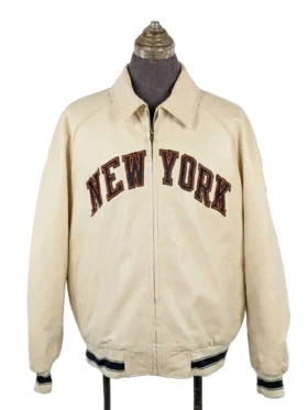 A full-zip collared jacket displayed on a mannequin from a three-quarter angle, featuring bold block lettering across the chest and a patriotic patch on the upper left sleeve.