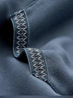 Close up of the braided stitch detail on the blue hoodie pocket.