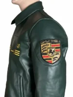 ight side profile view of the green Aimé Leon Dore × Porsche 993 leather jacket showing the gold embroidered 'ALD 993 PORSCHE' text marking on the upper right sleeve.
