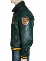 Left profile view of the Aimé Leon Dore × Porsche 993 leather jacket highlighting the detailed Porsche Stuttgart crest shield patch stitched onto the upper left arm. The dark green premium leather shows natural texture, clean shoulder seams, and side welt pockets.