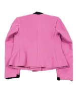 A full-length shot of a woman in a black Kennedy suit walking through a city, styled with black heels and dark sunglasses.