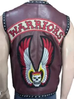 A view from behind Michael Beck, showing the large embroidered "The Warriors" patch with a flaming skull and wings on the back of the maroon leather vest.