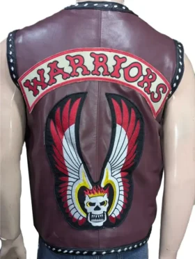 A view from behind Michael Beck, showing the large embroidered "The Warriors" patch with a flaming skull and wings on the back of the maroon leather vest.