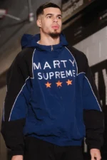 Side view of the Marty Supreme navy blue and black varsity jacket showing the sleeve piping.