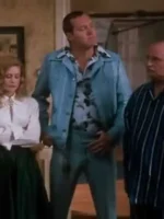 Randy Quaid as Cousin Eddie in powder blue leisure suit standing at Christmas Eve dinner party with wide collar and patterned shirt visible among other characters