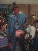 Randy Quaid as Cousin Eddie in powder blue leisure suit holding wrapped Christmas gift beside woman at Christmas tree in National Lampoon Christmas Vacation