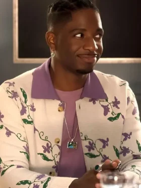 Samuel Arnold as Julien in Emily in Paris Season 5 wearing a vibrant purple cardigan with floral embroidery.