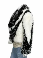 Erin Andrews standing on the NFL sidelines holding a microphone, wearing an oversized black and ivory faux fur coat with a massive sculptural collar.