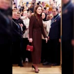 Full-length view of Kate Middleton wearing a burgundy plaid double-breasted coat outside Royal Marsden Hospital