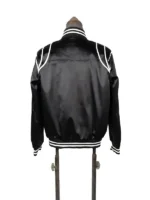 Rear perspective of the Keith Powers black satin varsity bomber jacket, showcasing the smooth seamless back canvas, drop-shoulder white arc trim, and striped rib-knit collar and hemline.