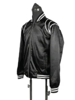 Left profile three-quarter studio view of the Keith Powers movie-inspired black satin varsity jacket, emphasizing the lustrous texture and flexible athletic drape.