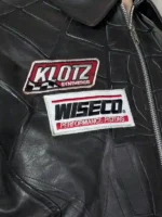 Full-length view of a black leather spider web jacket with rib-knitted cuffs and a reinforced hem for a wind-resistant fit.