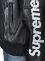 Close-up of the leather web graphic appliqué and embroidered logo patches on a red and blue Supreme Vanson racing jacket.