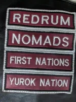 Detailed view of the artisanal embroidery and patch work on the back of a premium leather vest.