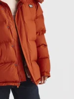 A full lifestyle display of the 1920 Orange Puffer Jacket showing its quilted chambers and bright citrus tone.