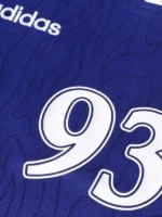 A full lifestyle display of the Adidas Bape 93 Flame Jersey featuring its vibrant fire graphics and dual-branded logos.