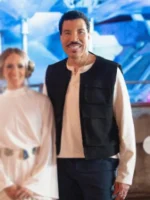 Lionel Richie wearing a black vest standing beside a woman in white outfit on American Idol 2026 set