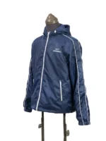 A three-quarter angled view of the blue BTS Keep Swimming lightweight hooded jacket. The shot showcases the front white zipper closure, white drawstring adjusters on the hood, and the minimal white text reading "KEEP SWIMMING" on the left chest.