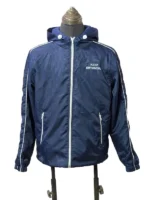 Full front-facing view of the BTS Keep Swimming blue jacket displayed on a mannequin. Features a central white zipper track, twin white-zippered hand pockets, a toggle-adjustable hood, and "KEEP SWIMMING" printed in clean white block letters across the left chest.