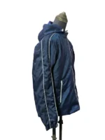 A true side profile view of the navy blue BTS Keep Swimming jacket on a mannequin. Highlights the full length of the sleeve featuring a thin white piping accent strip down the arm, an elastic cuff, and a visible vertical white zippered side pocket.
