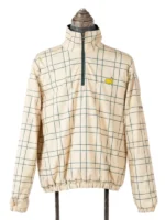 The front view of the beige and green checkered Masters Reversible Jacket on a mannequin stand, featuring a quarter-zip mock neck design and the iconic green and yellow Masters golf tournament tournament logo on the left chest.