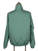 The back view of the fully reversed solid green Masters Reversible Jacket on a mannequin stand, displaying its smooth solid-colored panels and a structured elastic waistband.