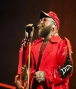 A detailed macro shot of the premium wool-blend fabric and intricate stitching on the Teddy Swims 3Arena Red Long Coat.