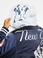 Close back view of BBC x NY Yankees navy satin bomber jacket with New York script and grey hooded insert