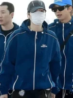 Multiple BTS members and staff wearing matching blue Keep Swimming jackets at airport
