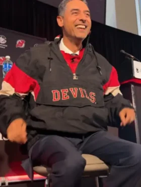 New Jersey Devils GM Sunny Mehta smiling at his 2026 introductory press conference wearing the vintage Devils Starter pullover jacket
