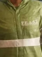 Close-up of F.E.A.S.T. chest logo with organization subtitle text white horizontal stripe and snap-tab zipper on green jacket