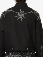 Back view of King Spider x Young Thug black denim jacket on model showing rhinestone spider web across upper back and shoulders