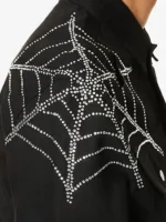 Close-up of rhinestone crystal spider web on the shoulder of King Spider x Young Thug black denim jacket