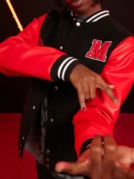 Close-up of Miles Morales varsity jacket M letter patch showing MILES text embroidered inside the red M with snap buttons and red leather sleeve visible