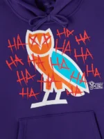 Close-up of OVO owl graphic in orange and teal with red HA HA HA Joker text on chest of purple 2026 hoodie
