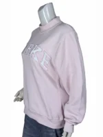 Three-quarter side angle view of a pink varsity sweatshirt highlighting the raised mockneck collar and the textured block letter embroidery.