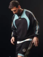 A premium standalone profile presentation of the black and blue Adidas Kith Lionel Messi Fleece Sweater.
