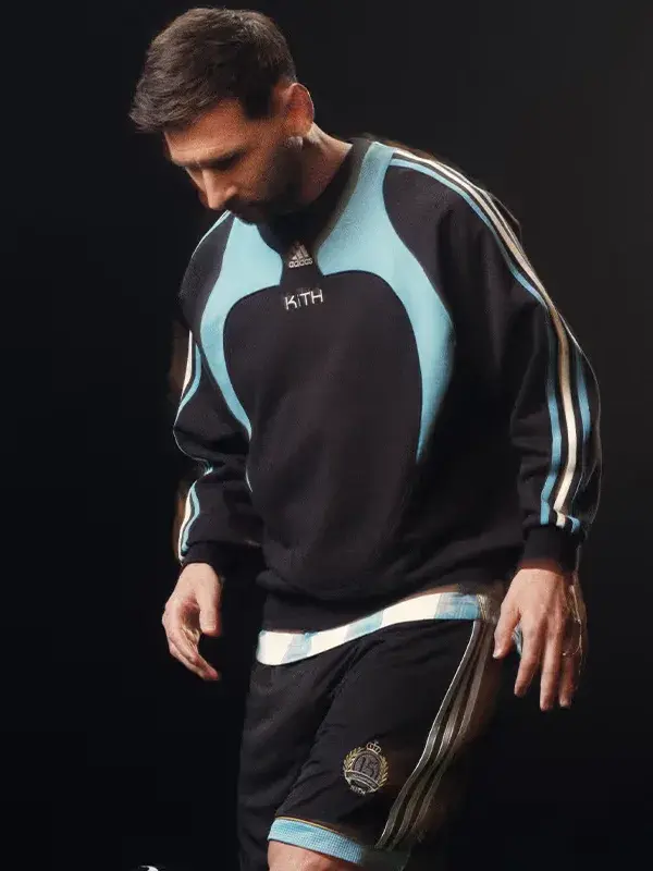 A premium standalone profile presentation of the black and blue Adidas Kith Lionel Messi Fleece Sweater.