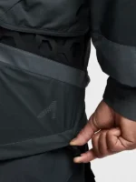 Close-up of Nike ISPA Butterfly Jacket Anthracite hem drawcord adjuster with black hexagonal rubber overlay panel and ISPA dot-print logo