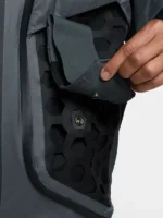 Hand detaching modular snap pocket from Nike ISPA Butterfly Jacket Anthracite showing brass snap button on black hexagonal rubber grid panel