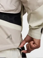 Close-up of Nike ISPA Butterfly Jacket Orewood Brown hem adjuster drawcord with black hexagon rubber panel and ISPA logo print detail