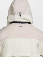 Back hood detail of Nike ISPA Butterfly Jacket in Natural Orewood Brown showing structured hood, buckle closure, back zip seam and Nike Swoosh